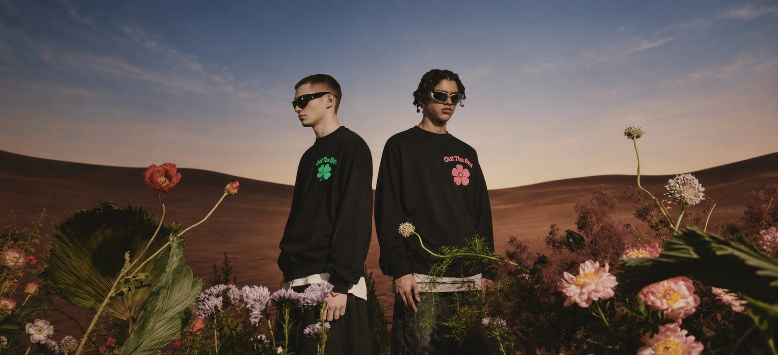 Twee modellen in Lucky en Bloom tussen hoge bloemen, met heuvels en een avondlucht